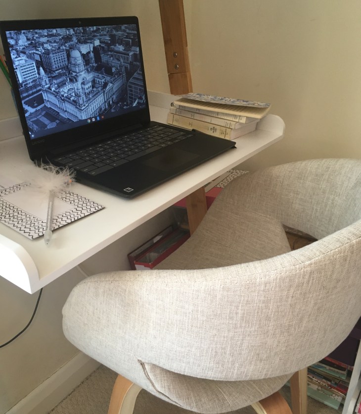 Small desk set up with laptop and chair