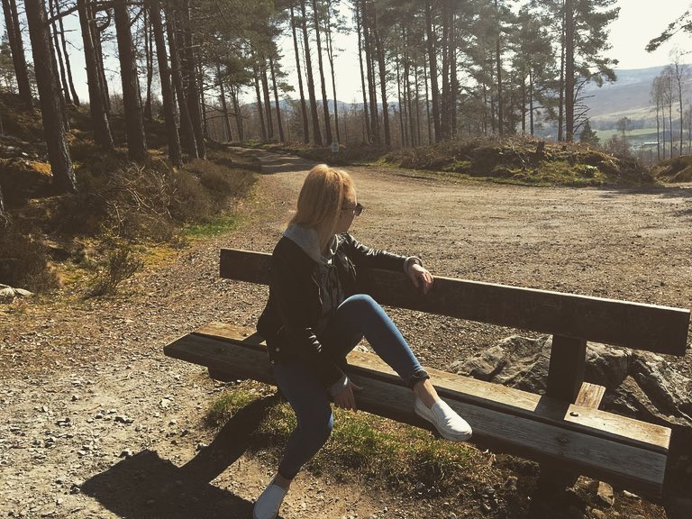 Woman poses on a bench and stares into a forest