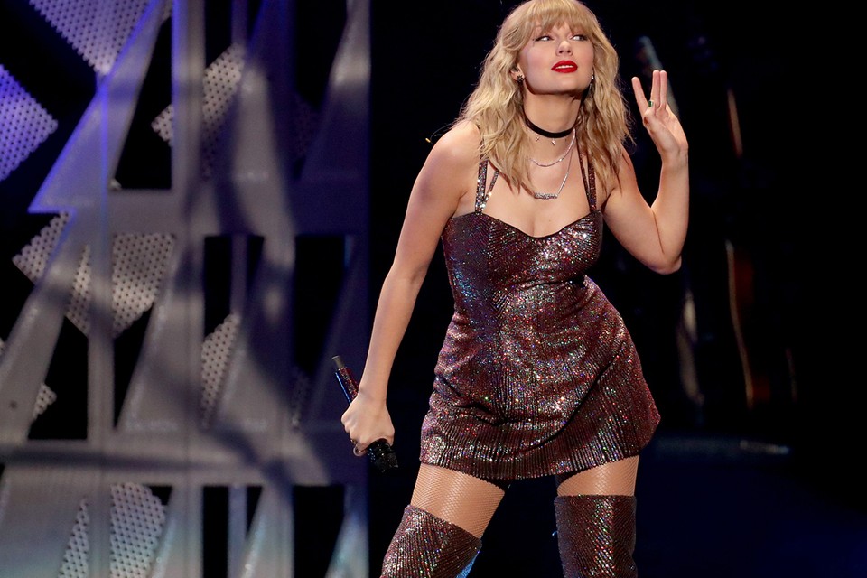 Taylor Swift performs on the stage for her fans, wearing a brown glittery dress and boots.