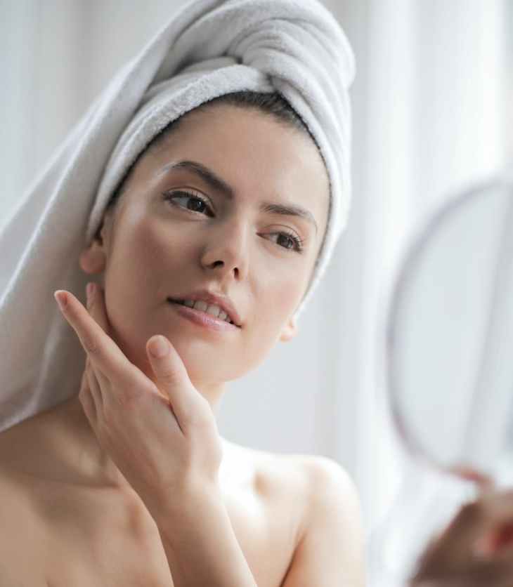 Woman inspects her face in the mirror