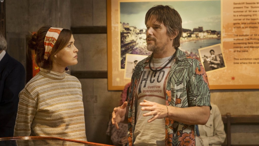 A still from the 'Juliet, Naked'. The two characters of 'Juliet, Naked' chat. The woman frowns.