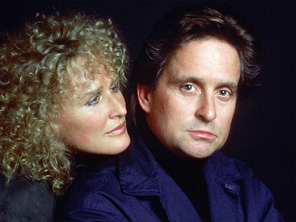 The two characters from 'Fatal Attraction' embrace. The man looks at the camera with concern.