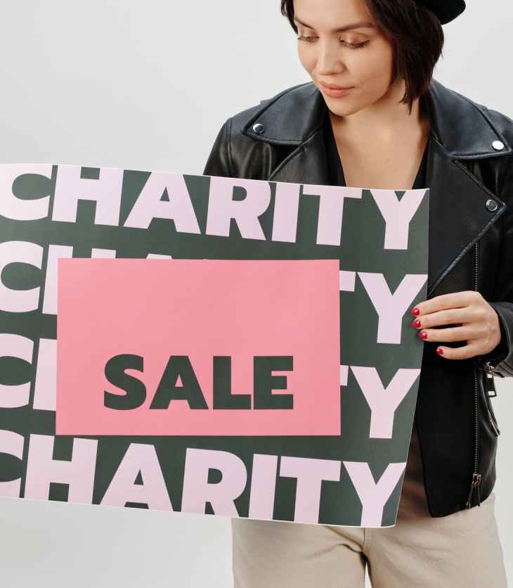 woman in black leather jacket holding green and white charity sign