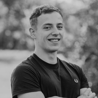 Young man in black and white stands with his arms crossed