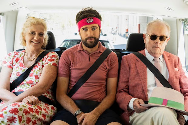 Image from the series 'Jack Whitehall: Travels with my Father'. Three people pose for the camera in the back of a car.