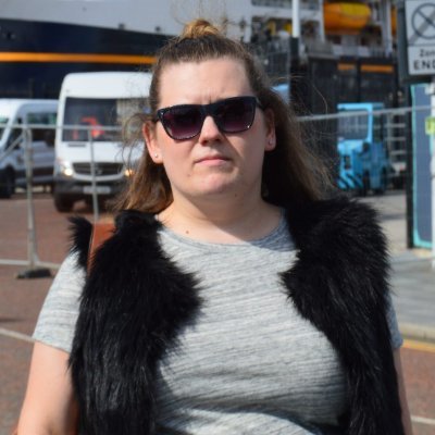 A woman stares at the camera, with a pair of sunglasses
