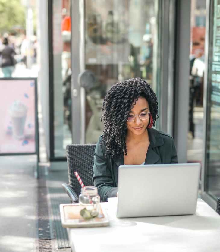Woman starts her own blog on a laptop outside a café