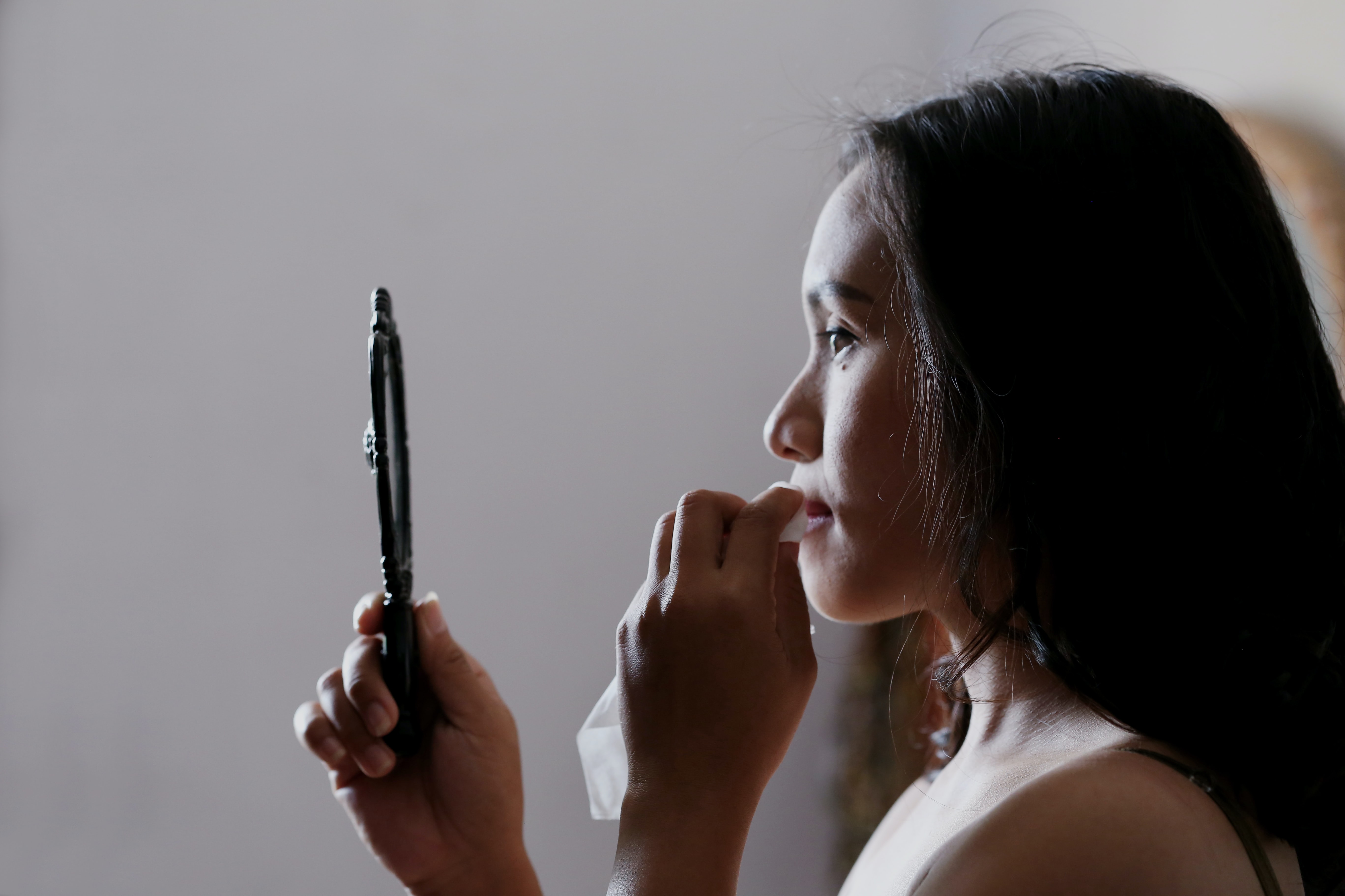Woman taking off make-up in the mirror- body image mindset