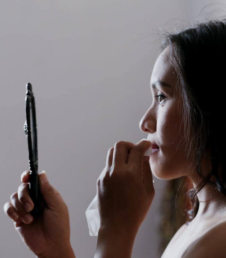 Woman taking off make-up in the mirror- body image mindset