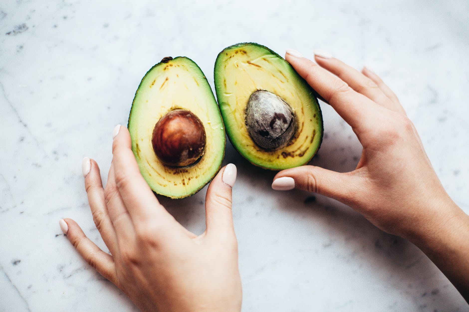 person holding sliced avocado, healthy food