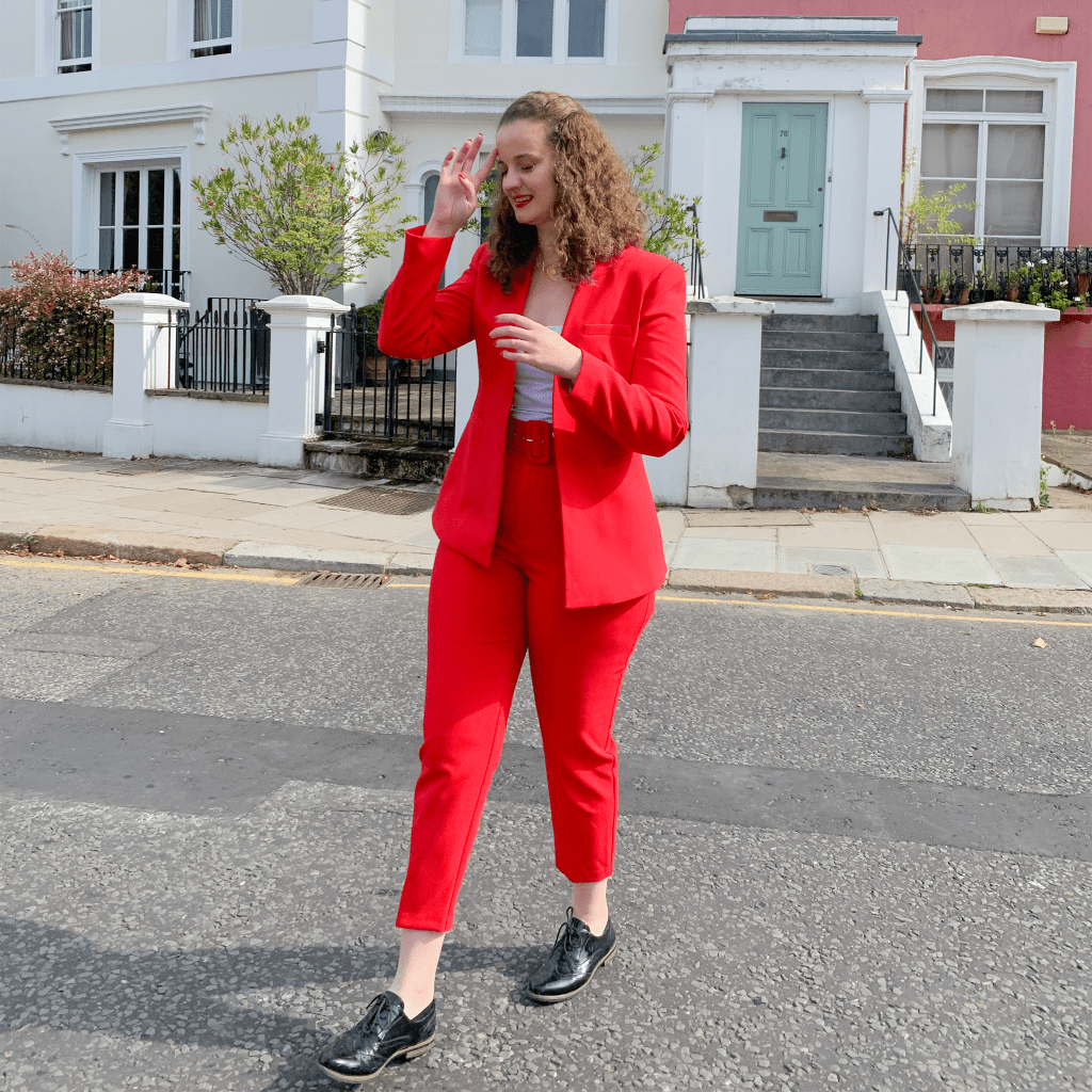 A young woman stands in a stylish suit in the middle of a street