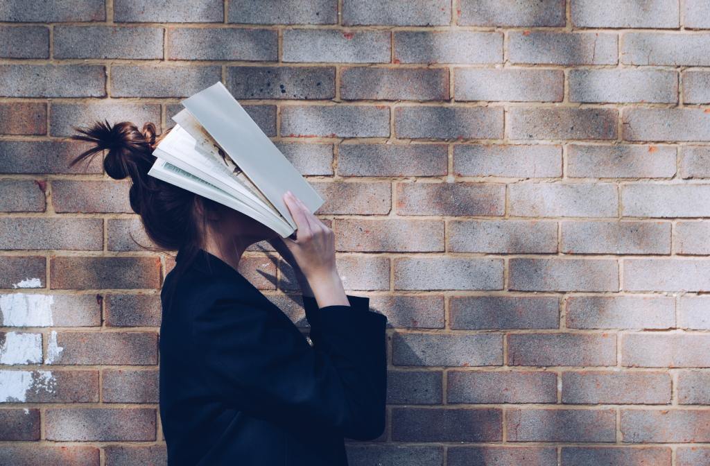 person with book on head in stress and burn-out