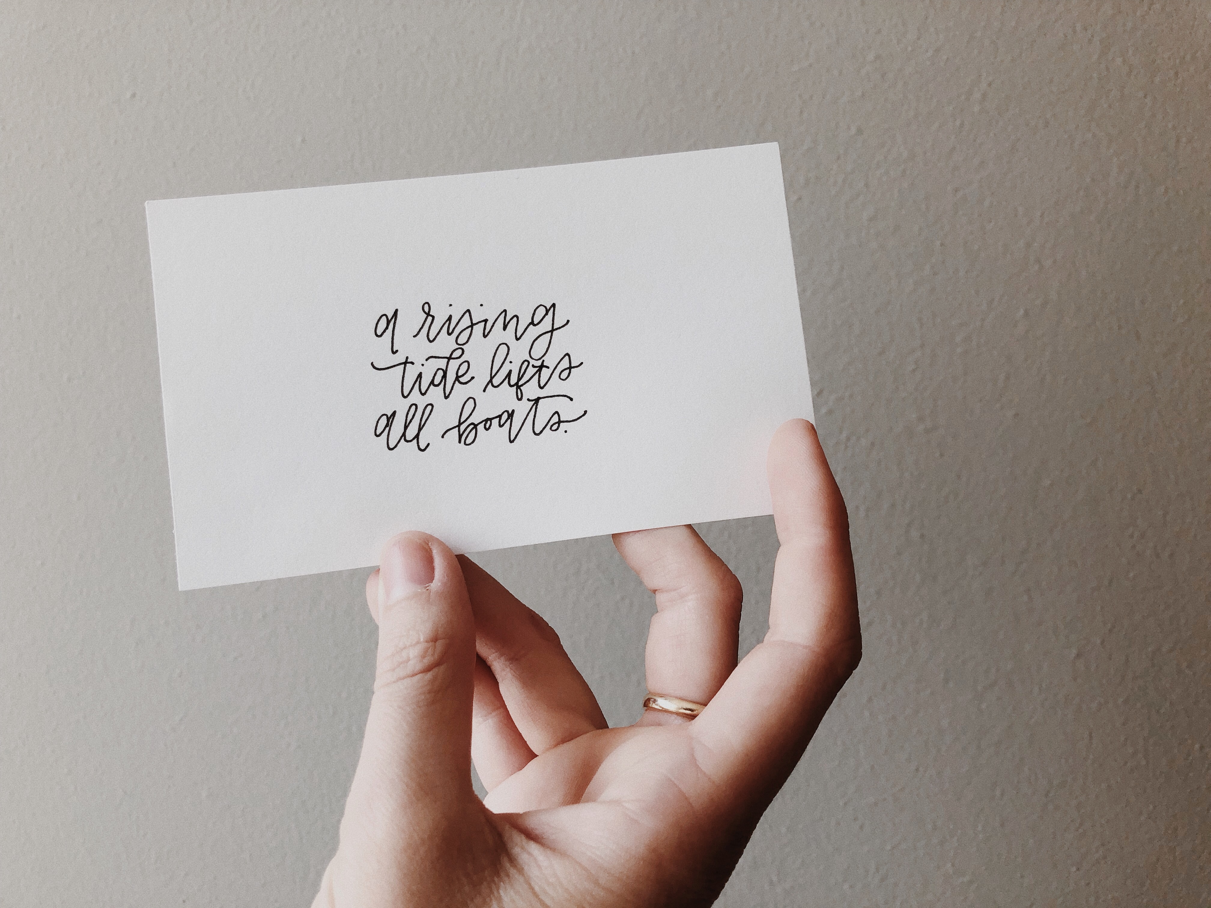 piece of card with "a rising ride lifts all boats" handwritten on it