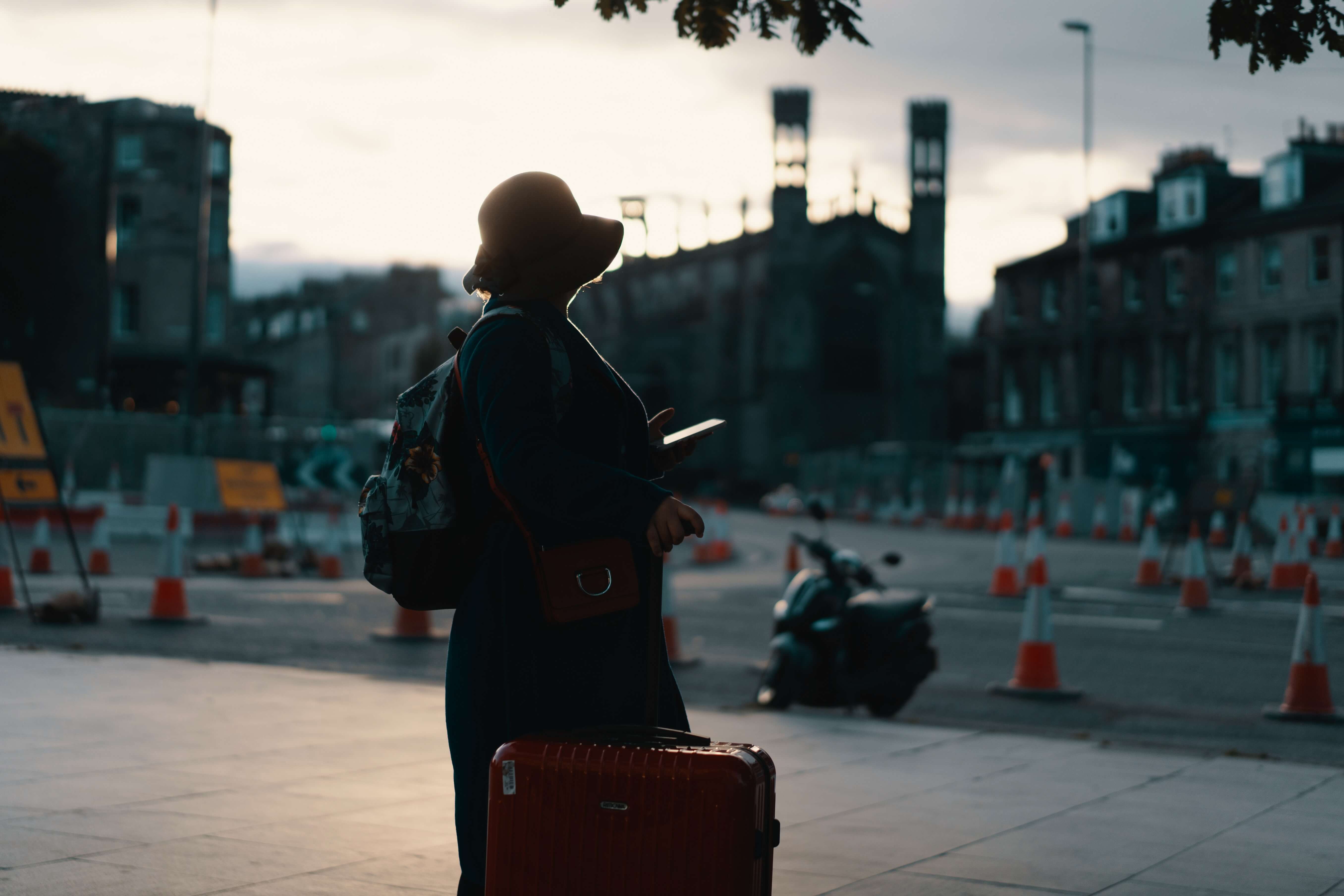 person looking at phone with a suitcase on a road