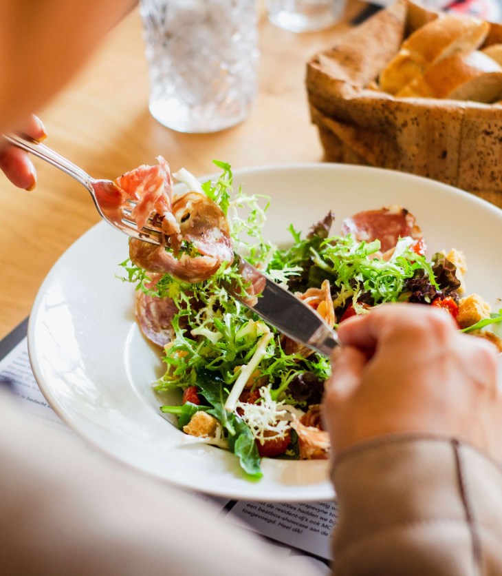 someone eating a bowl of salad with a tub of bread