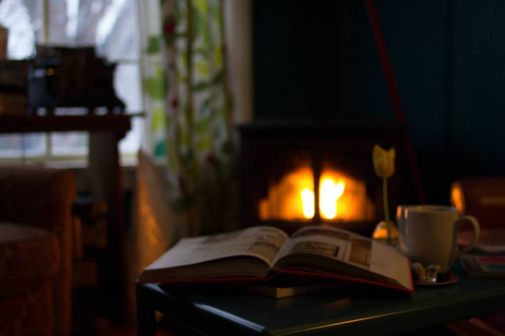 an open book in front of a fireplace: romanticise your Autumn
