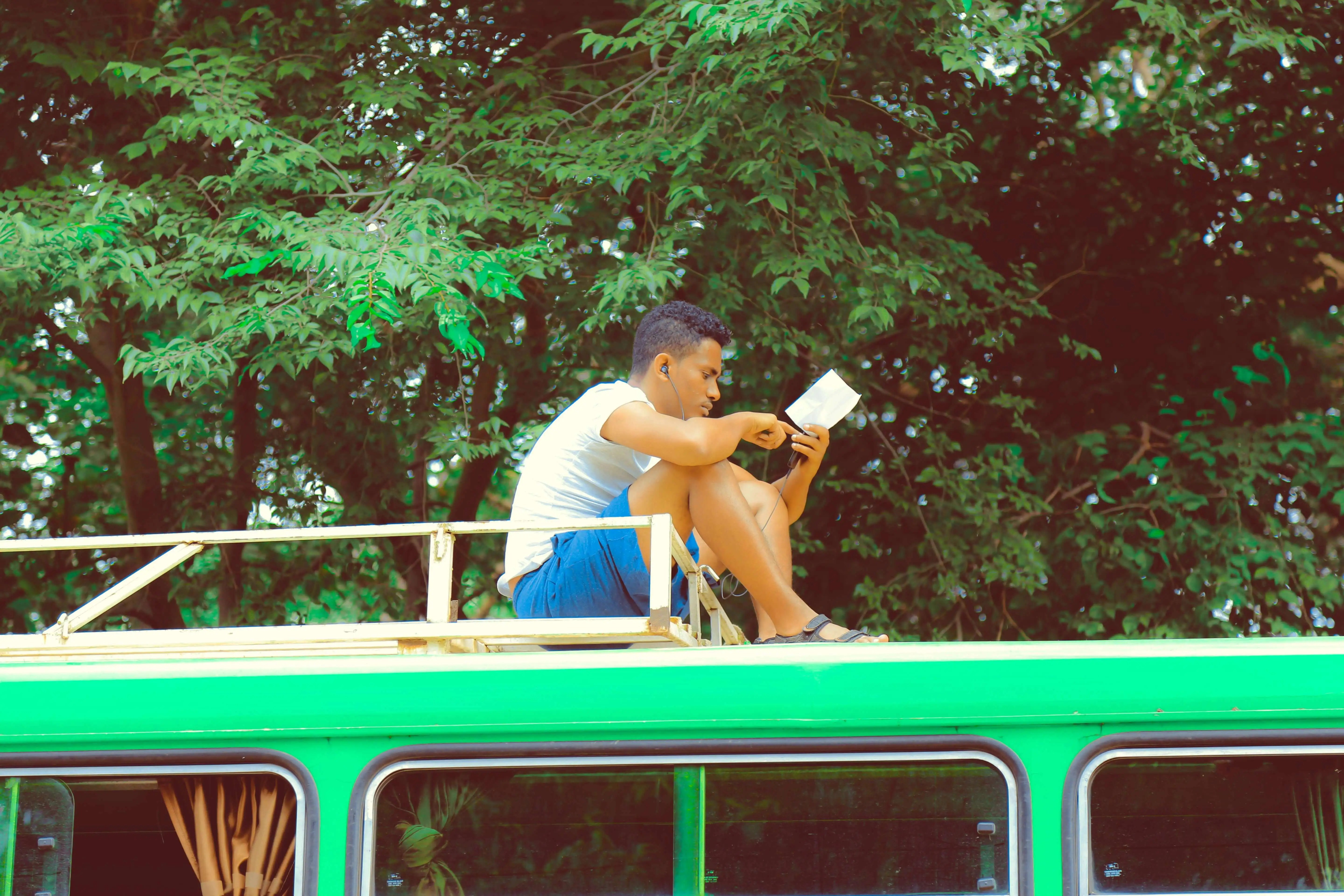 person sat reading a book on top of a bus: tips to make time for reading for pleasure