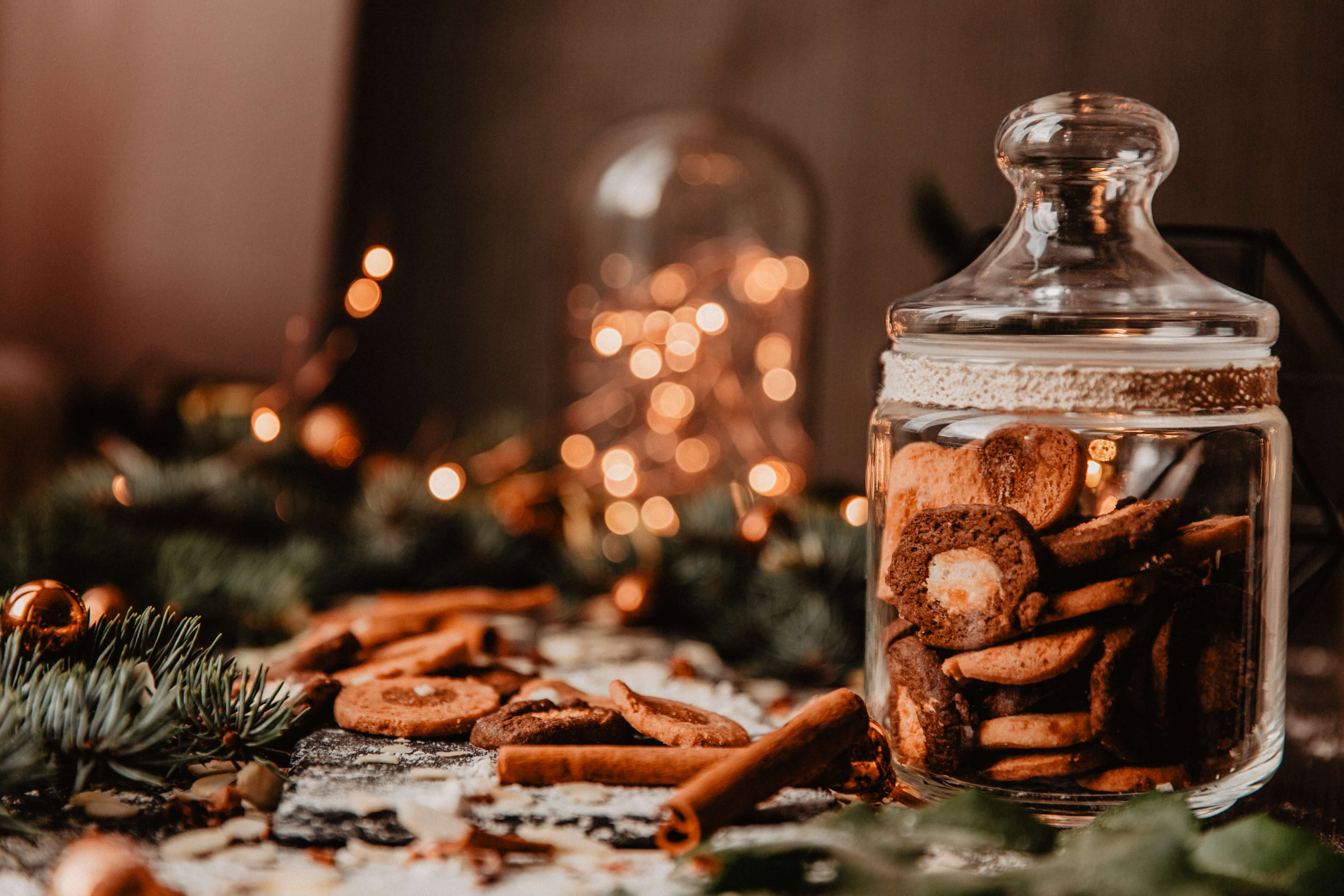 cosy Christmas lights and pine needles with jars of cookies and cinnamon sticks