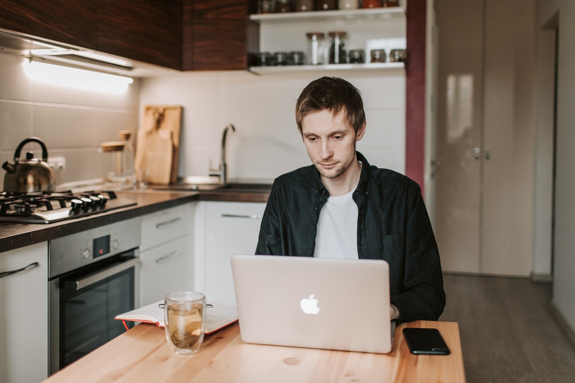 thoughtful man working on laptop in kitchen at home