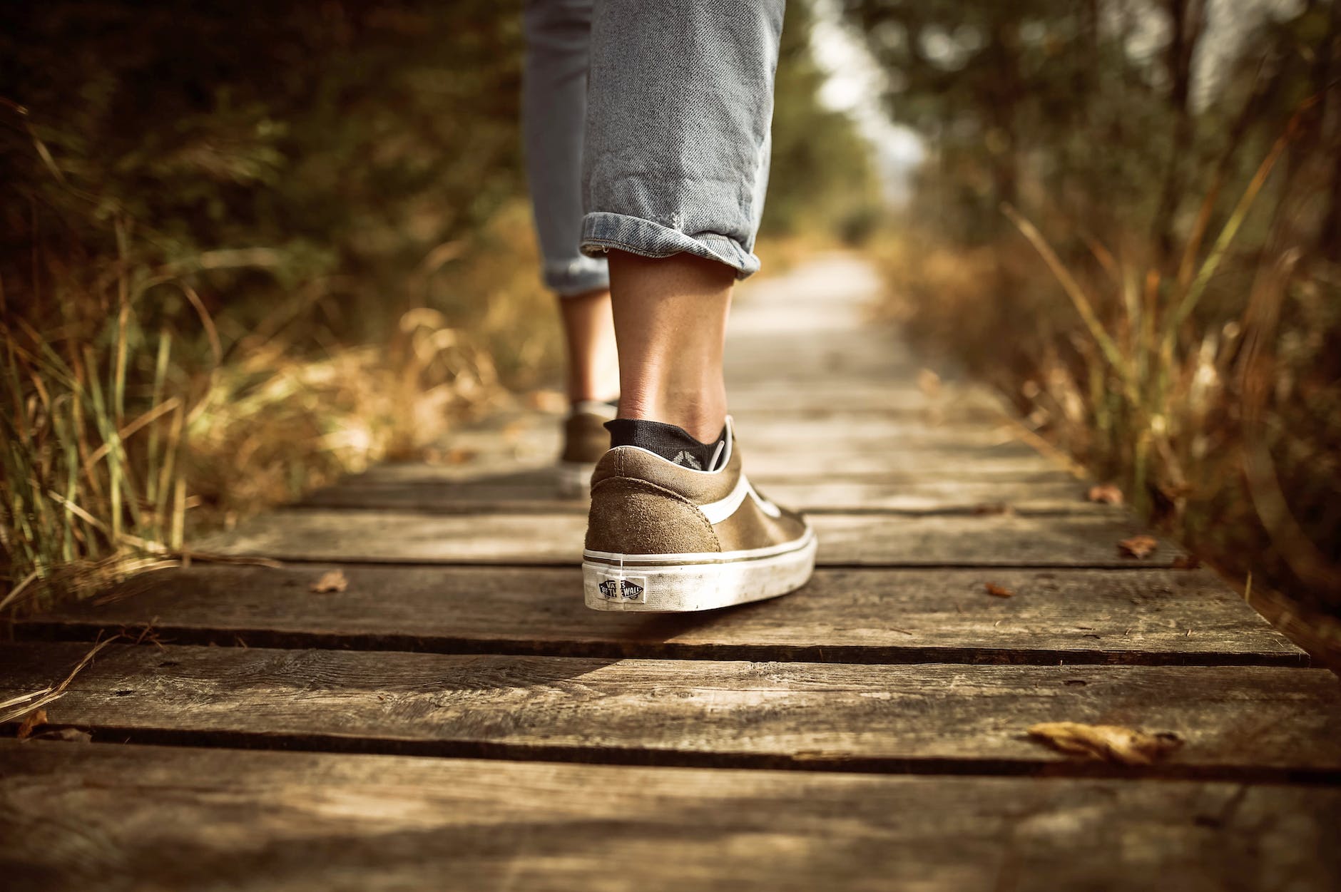 person stands on brown wooden pathway