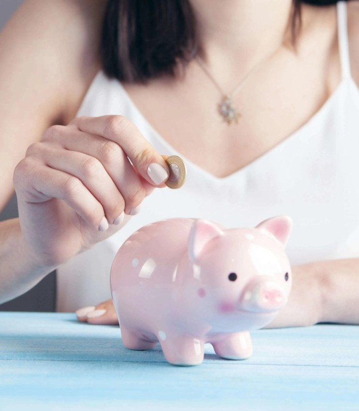 person putting a coin in a piggy bank