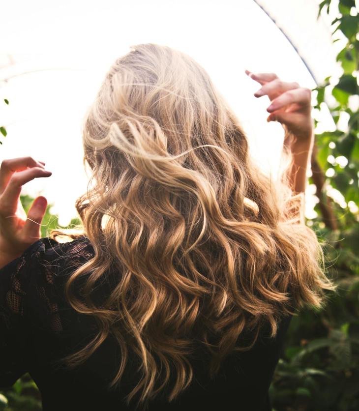 blonde haired woman standing between green plants