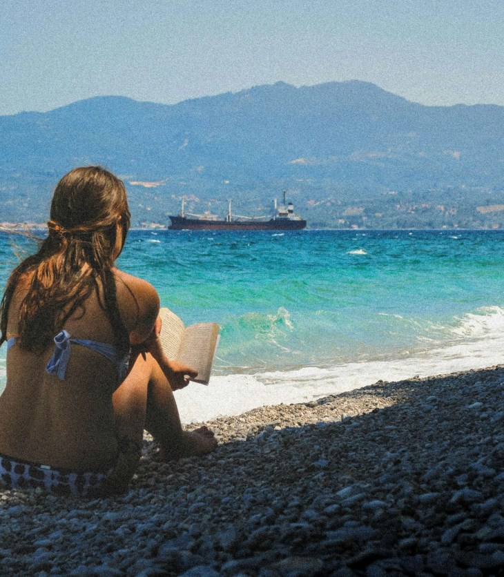 woman in bikini reading a book on a beach