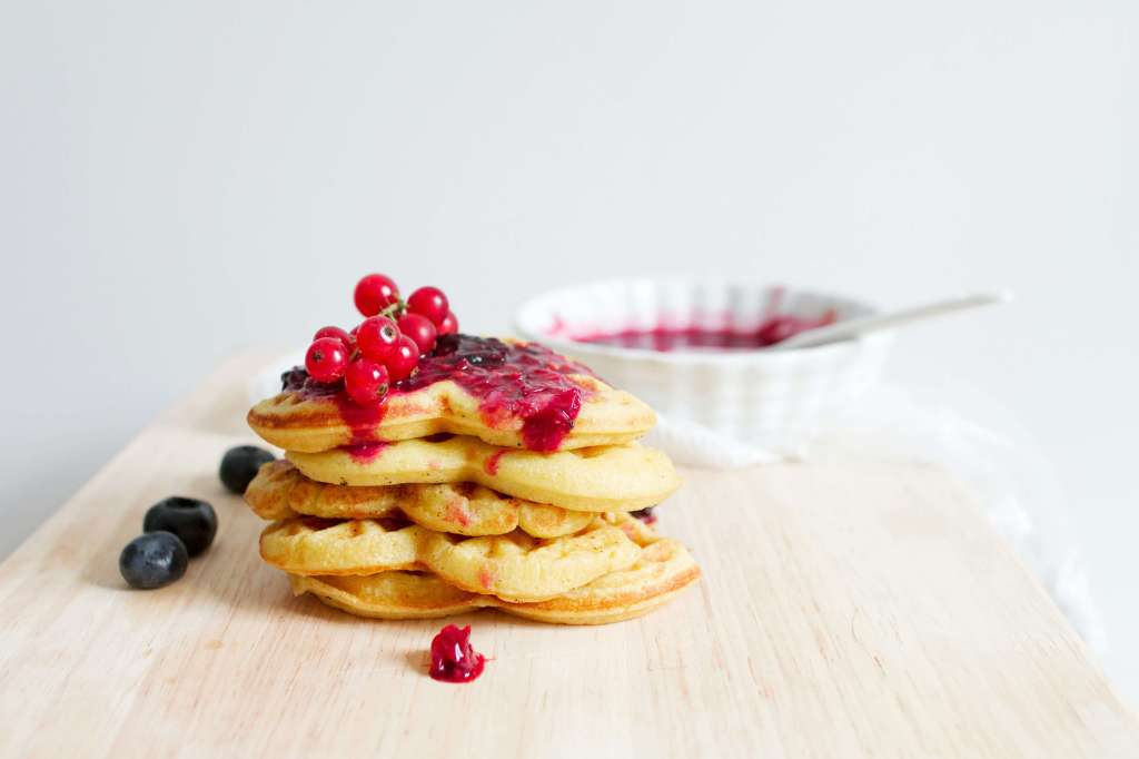 a pile of pancakes with berry sauce and berries on top