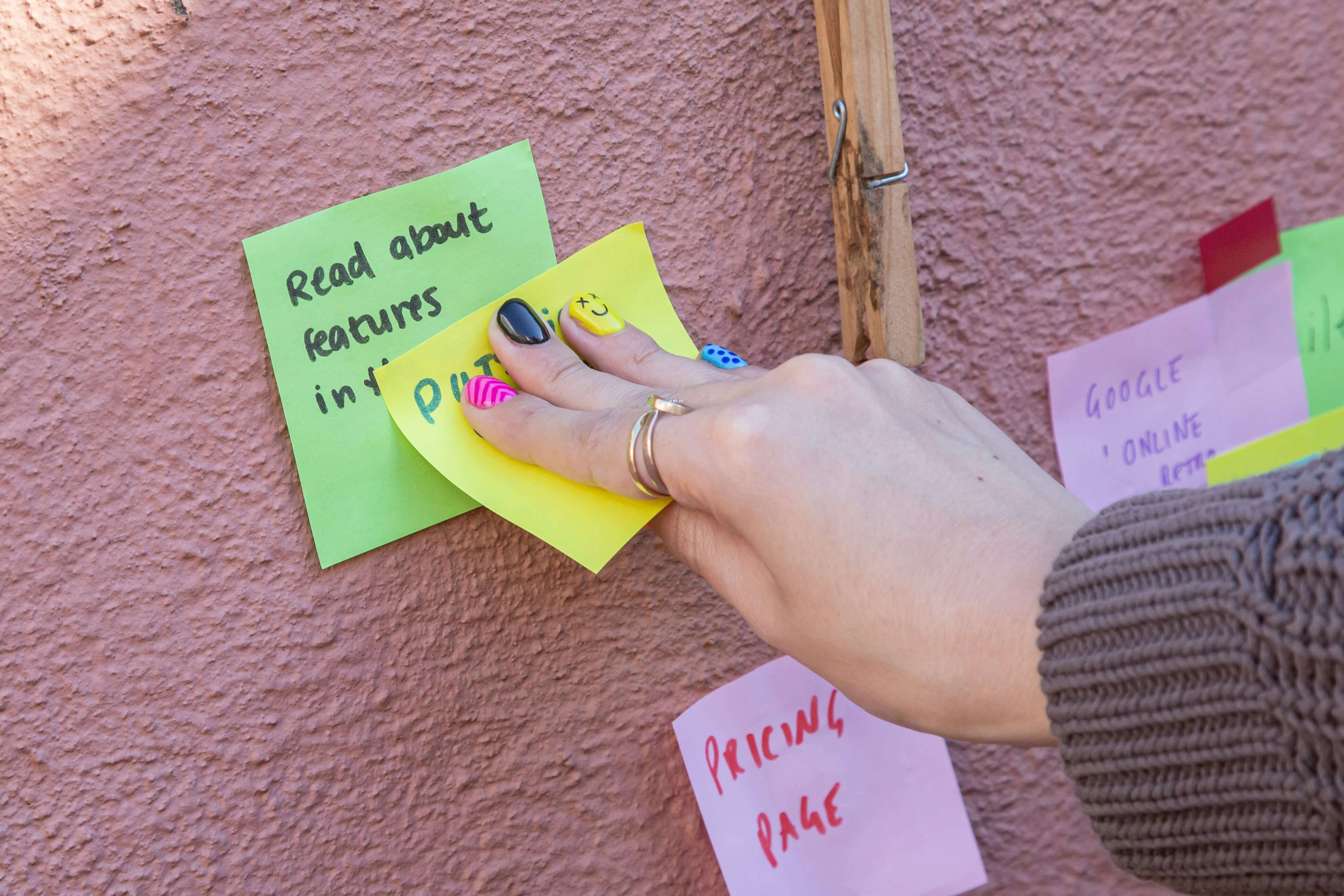 person sticking post-it notes on a wall: diversify your income streams
