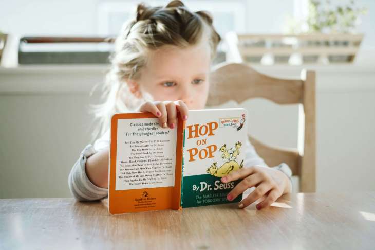 young child reading a book at a desk