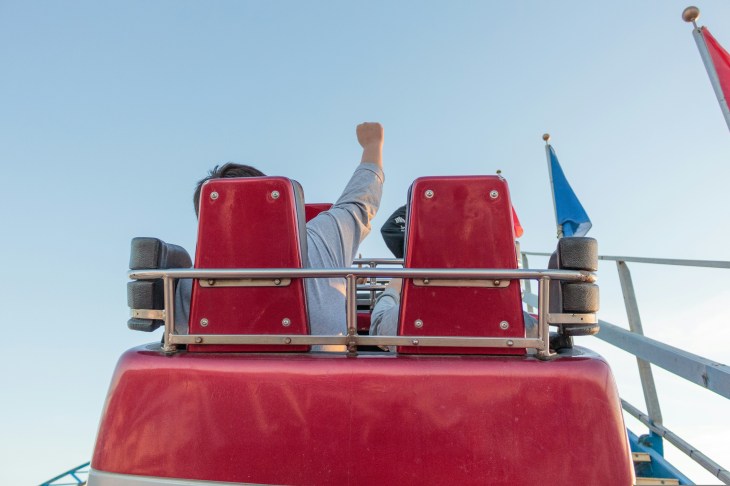 back of a rollercoaster seat with a person fist pumping the air
