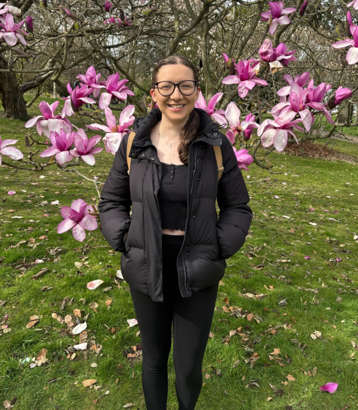 young woman stood under a Magnolia tree smiling