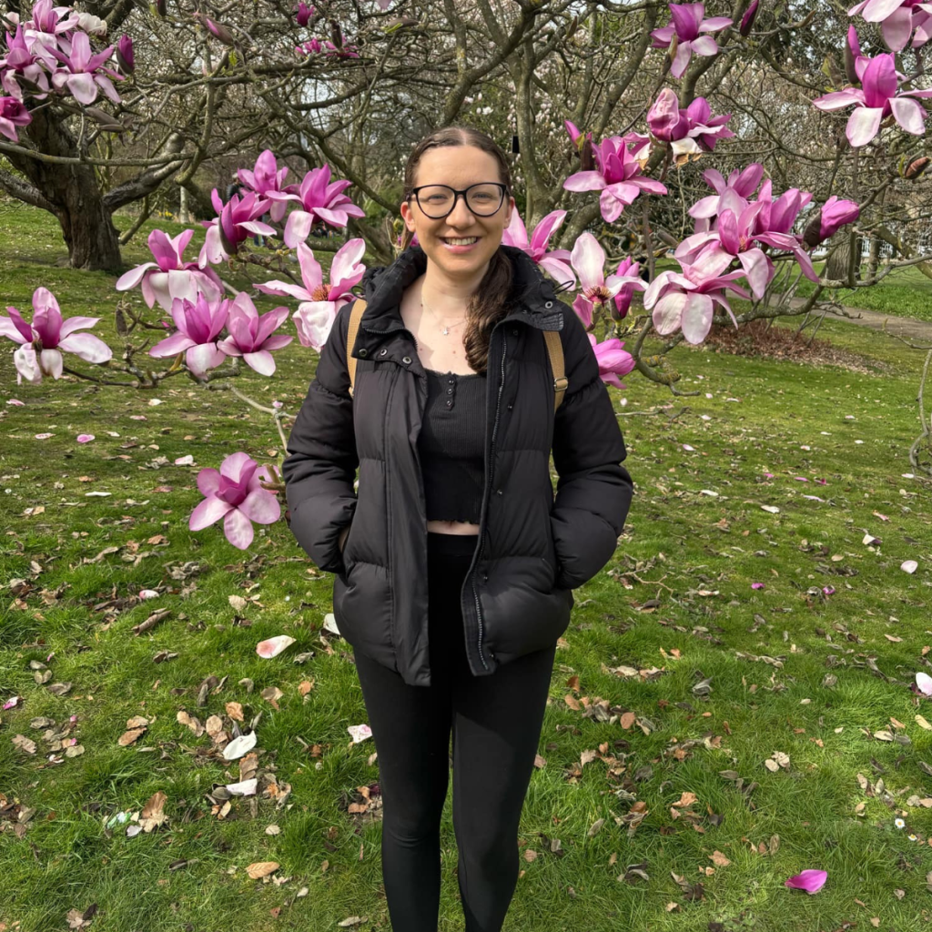 young woman in front of a Magnolia tree smiling