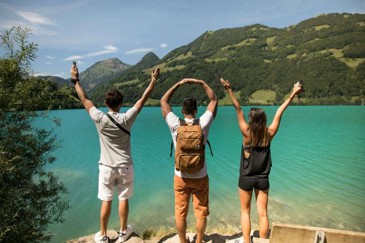 three people stood at a lake with their backs to the camera