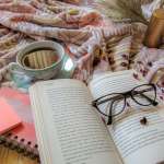 open book with glasses on and a teacup with a blanket
