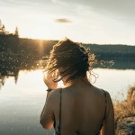 person by a lake flicking wet hair