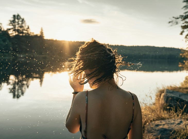 person by a lake flicking short wet hair