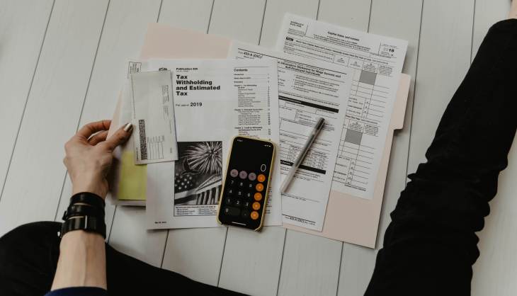 papers and documents on a table, including a calculator and pen