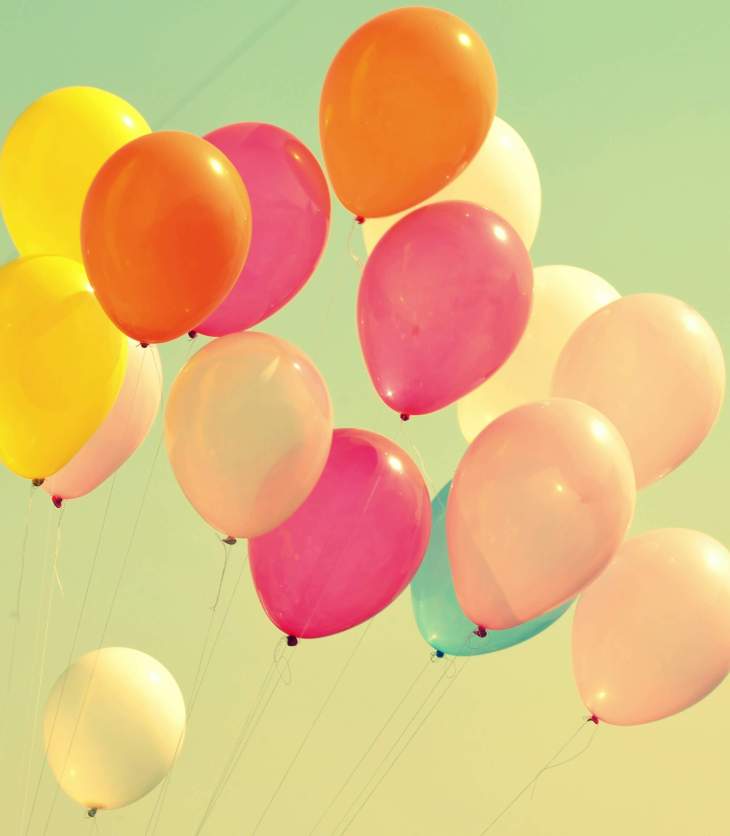 a bunch of multi-coloured balloons flying in the air