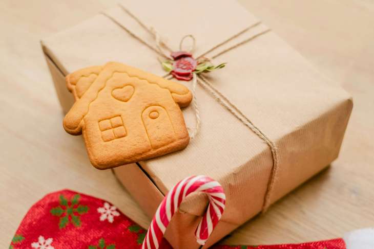 gift in brown parcel paper with a gingerbread biscuit, part of a stocking, and part of a candy cane