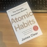 a copy of james clear' Atomic Habits laying on a desk and keyboard