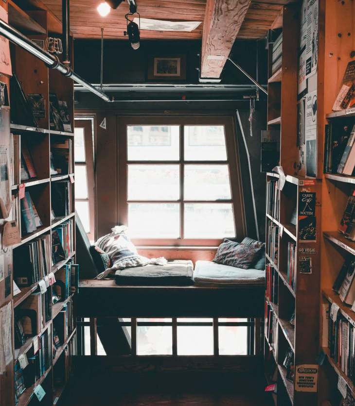 cushions in a window with book shelves all around it to create a cosy reading nook